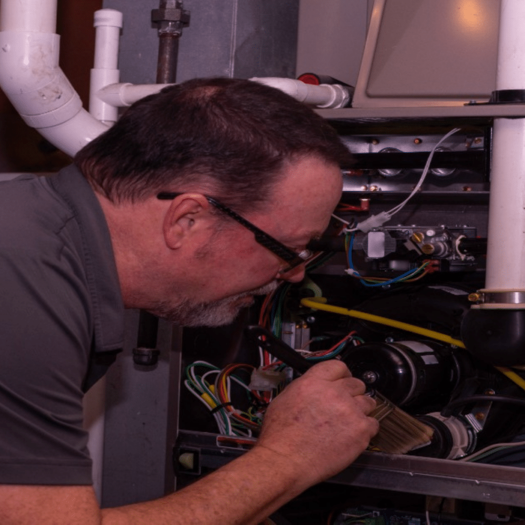 technician looking into furnace for heater maintenance